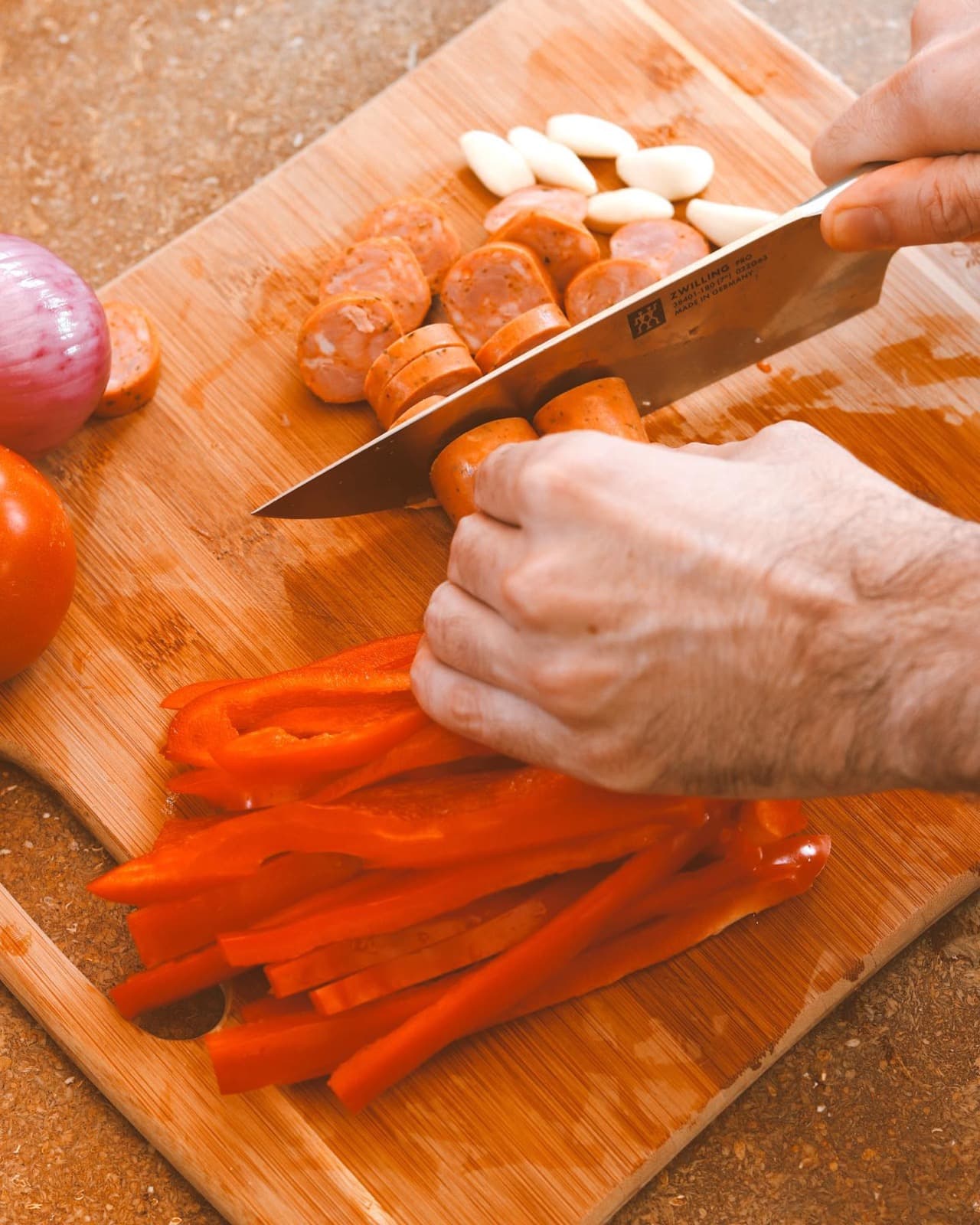 Manos cortando pimentón y chorizo para el sofrito
