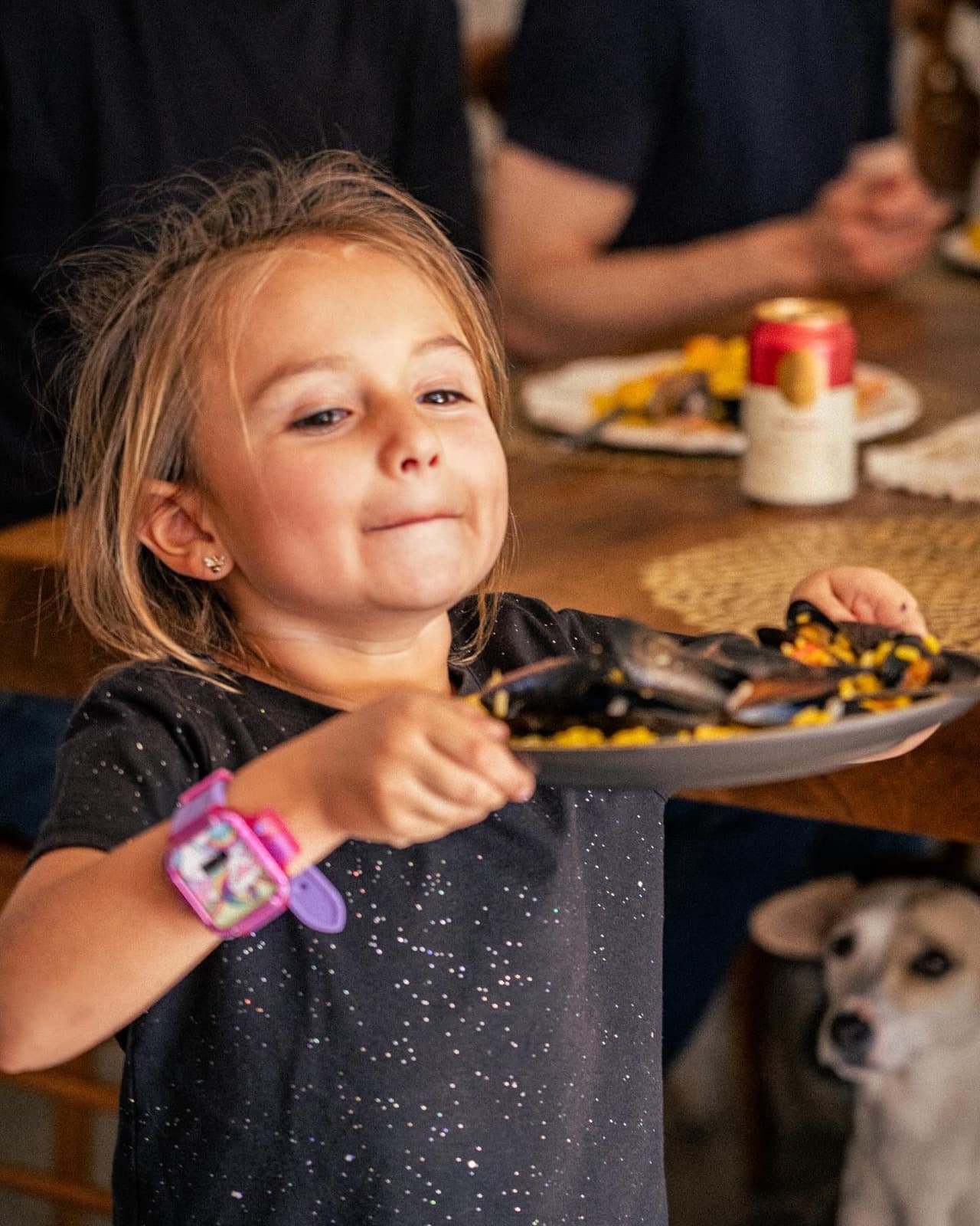 Una niña lleva su plato de paella